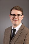 Picture of Andrew Schwenk, a young man with brown hair and glasses