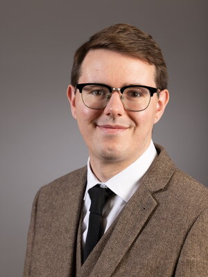 Picture of Andrew Schwenk, a young man with brown hair and glasses