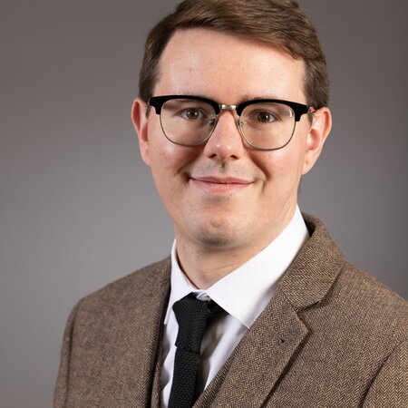 Picture of Andrew Schwenk, a young man with brown hair and glasses